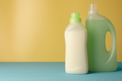 Photo of Bottles of fabric softener on light blue table, space for text