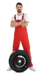 Full length portrait of professional auto mechanic with wheel and lug wrench on white background