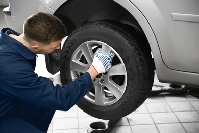 Photo of Young mechanic changing wheel at tire service