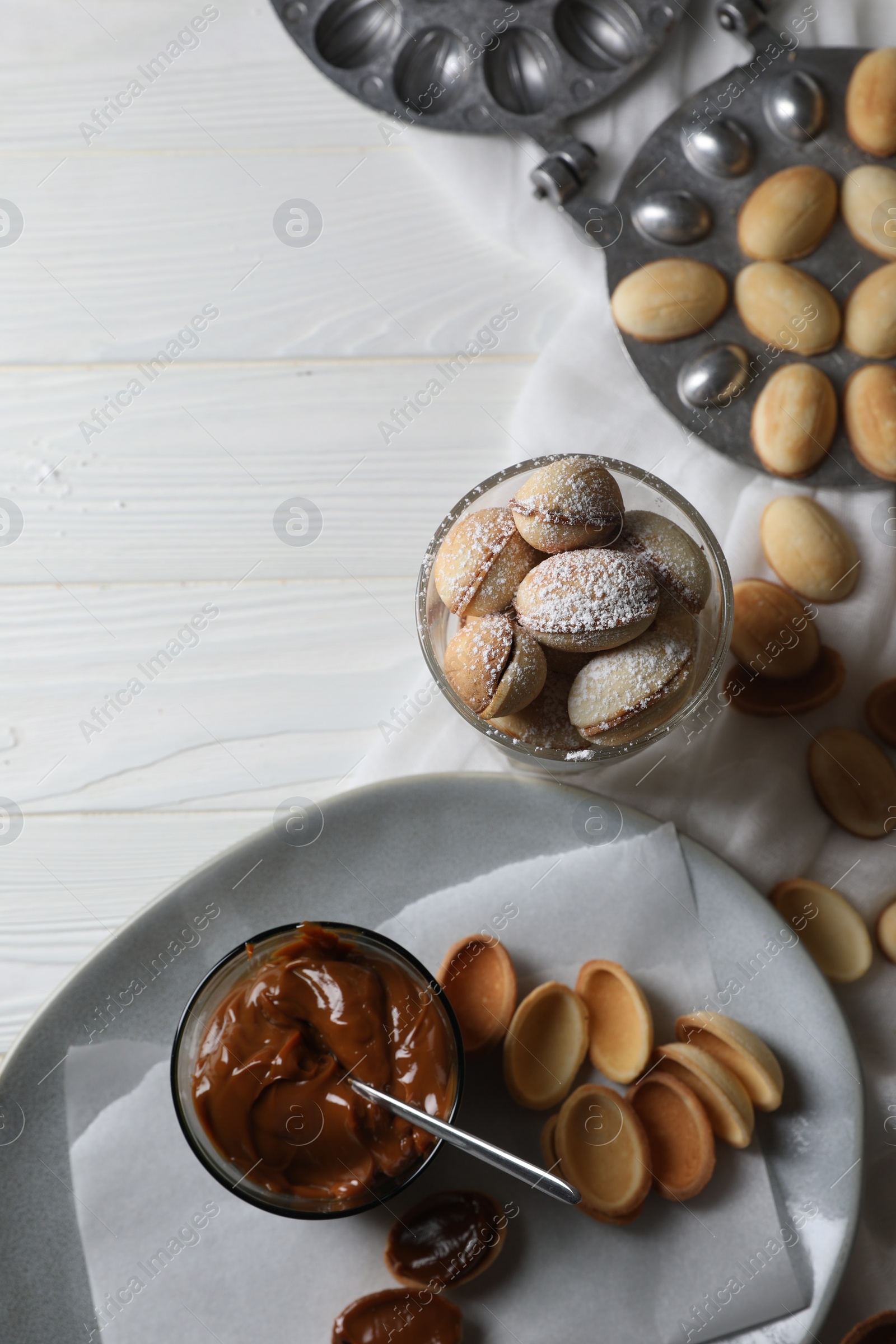Photo of Delicious walnut shaped cookies with condensed milk on white wooden table, flat lay