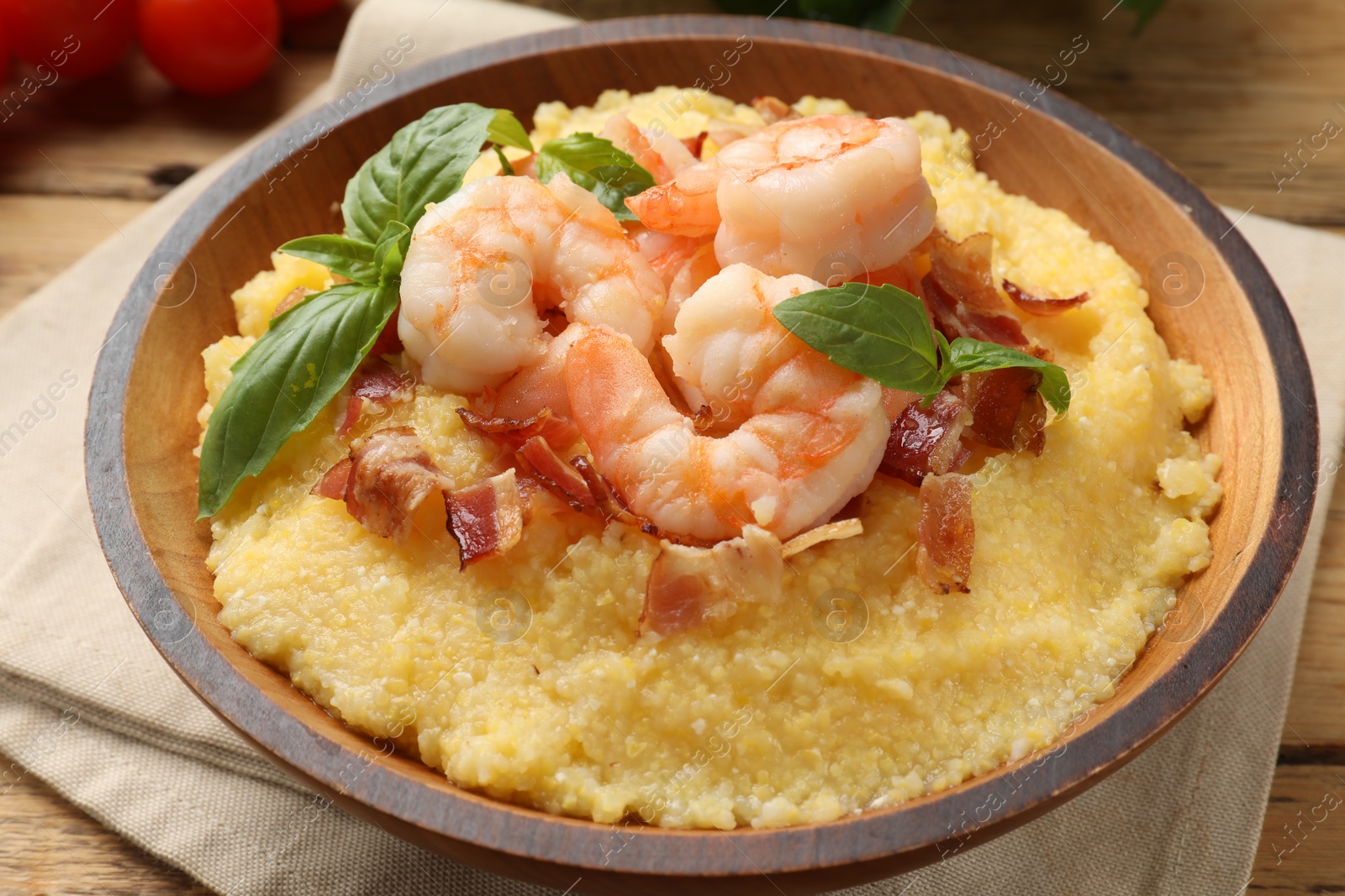 Photo of Fresh tasty shrimps, bacon, grits and basil in bowl on table, closeup