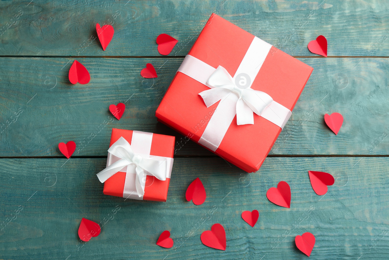 Photo of Beautiful gift boxes and paper hearts on wooden table, flat lay. Valentine's Day celebration