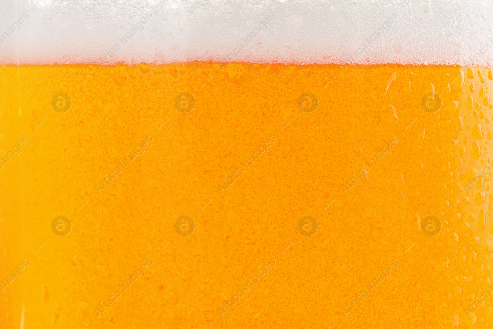 Photo of Glass of tasty cold beer with foam and condensation drops as background, closeup