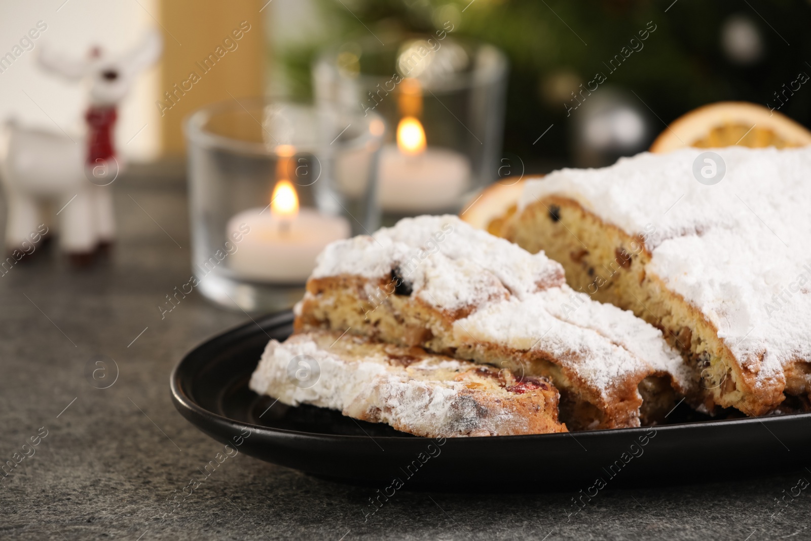 Photo of Traditional Christmas Stollen with icing sugar on grey table, closeup