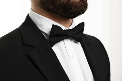 Photo of Man in suit, shirt and bow tie indoors, closeup