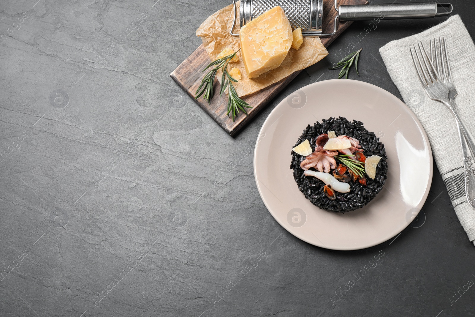 Photo of Delicious black risotto with seafood on grey table, flat lay. Space for text