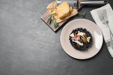 Delicious black risotto with seafood on grey table, flat lay. Space for text