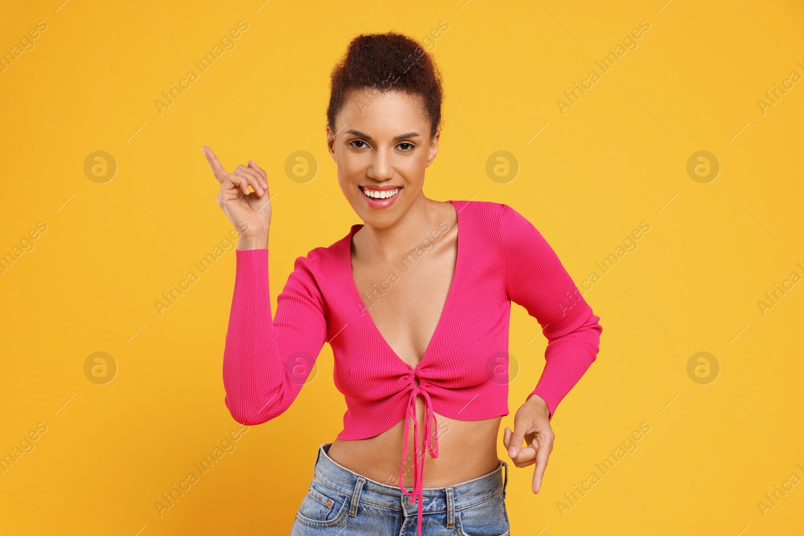 Photo of Happy young woman dancing on orange background