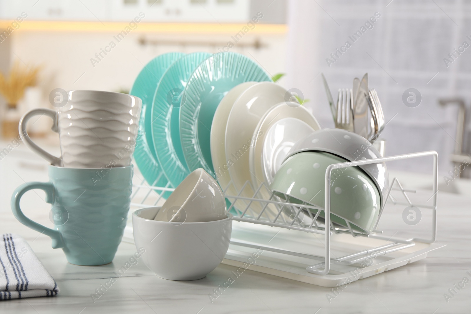 Photo of Many different clean dishware and cups on white marble table in kitchen