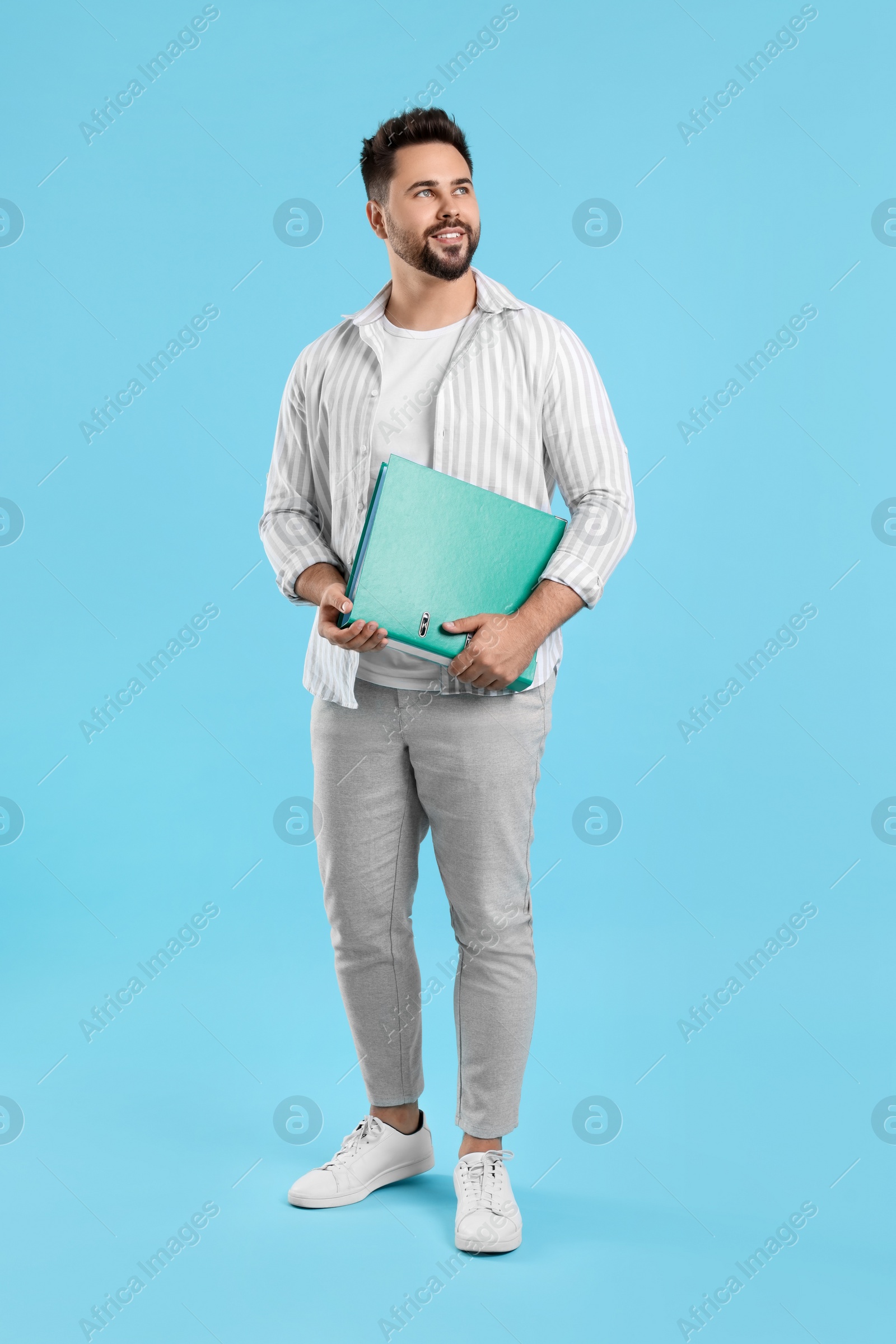 Photo of Happy man with folder on light blue background