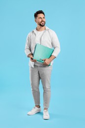 Happy man with folder on light blue background