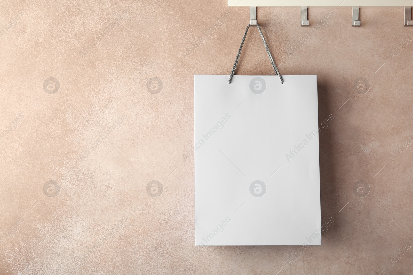 Photo of Rack with paper shopping bag on color wall. Mockup for design