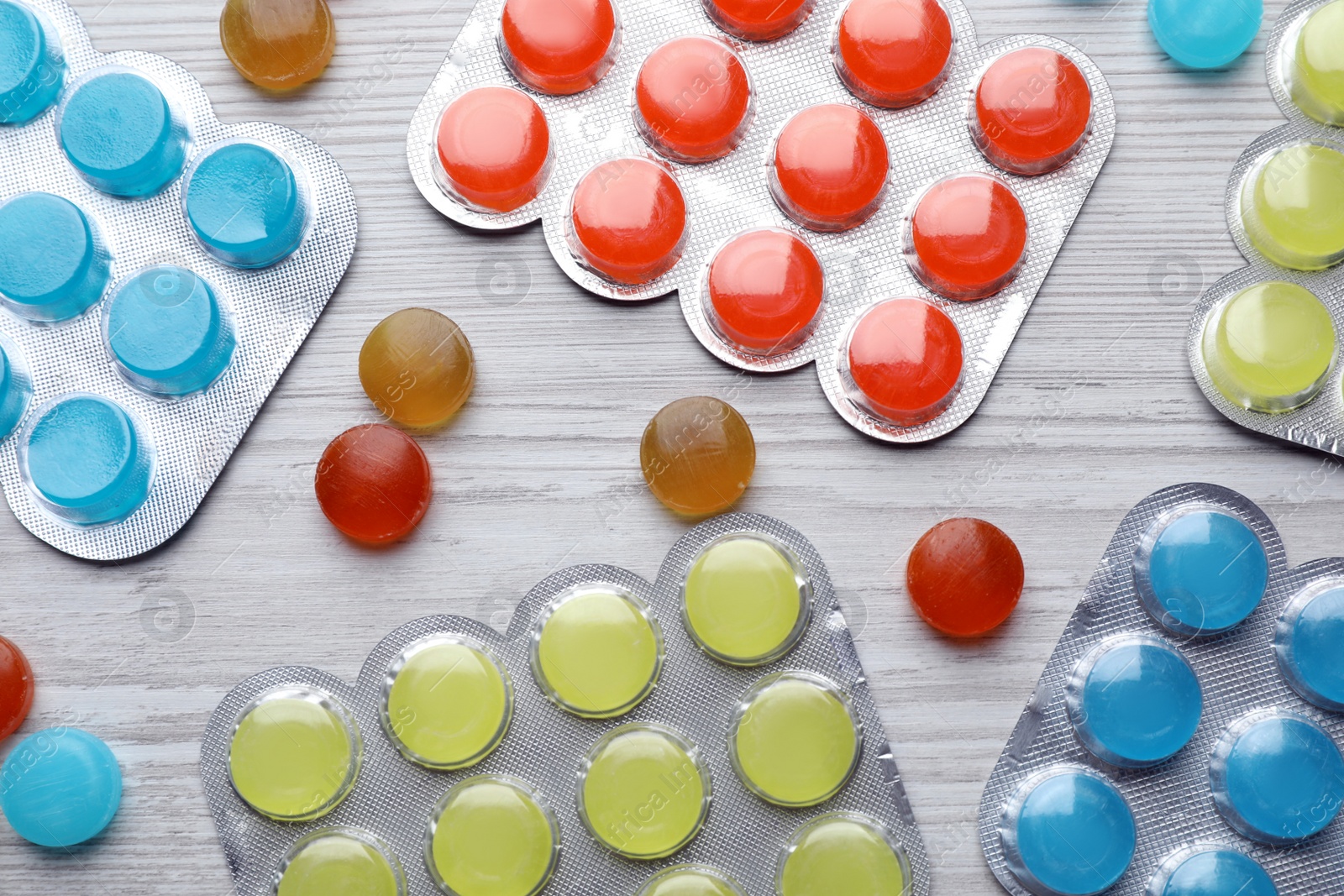 Photo of Colorful cough drops on white wooden background, flat lay