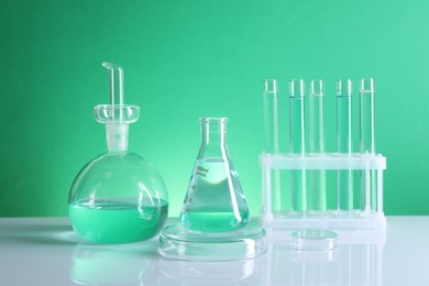 Photo of Laboratory analysis. Different glassware on table against green background