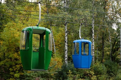 Photo of View of cableway with bright cabins in park on autumn day