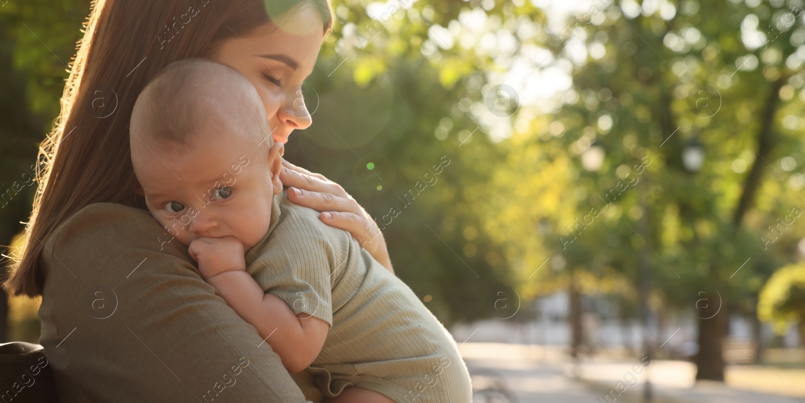 Image of Happy mother with cute baby in park on sunny day, space for text. Banner design 