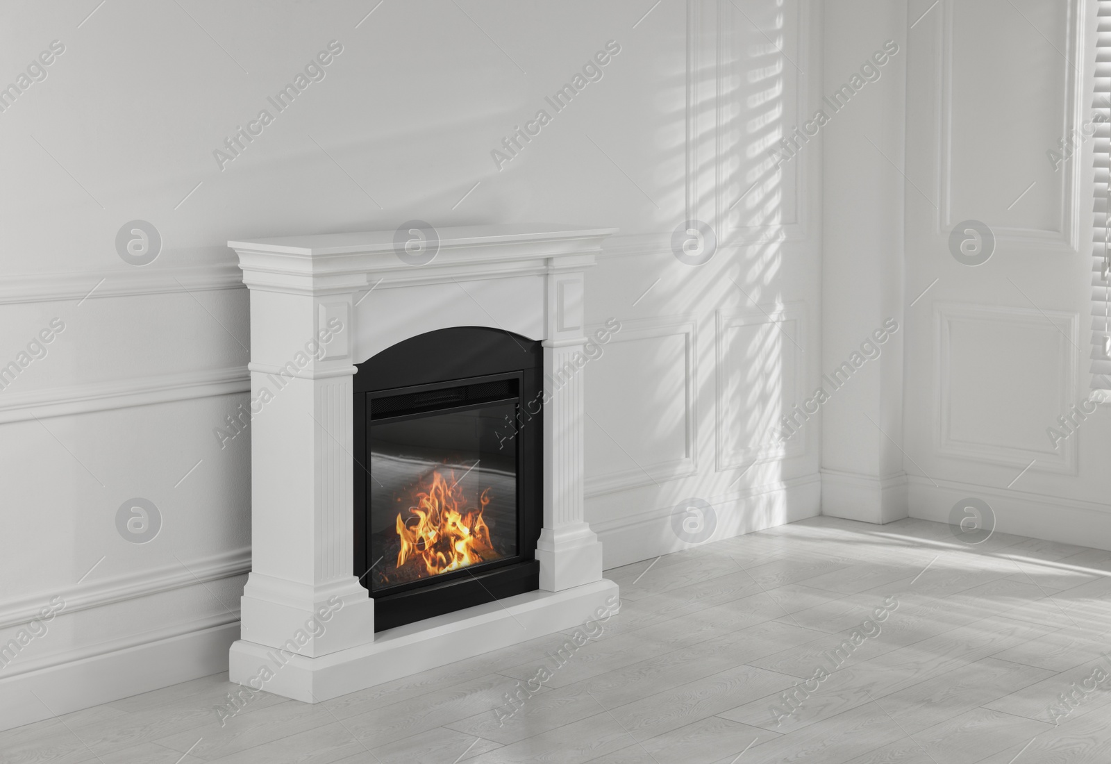 Photo of Modern electric fireplace near white wall in room