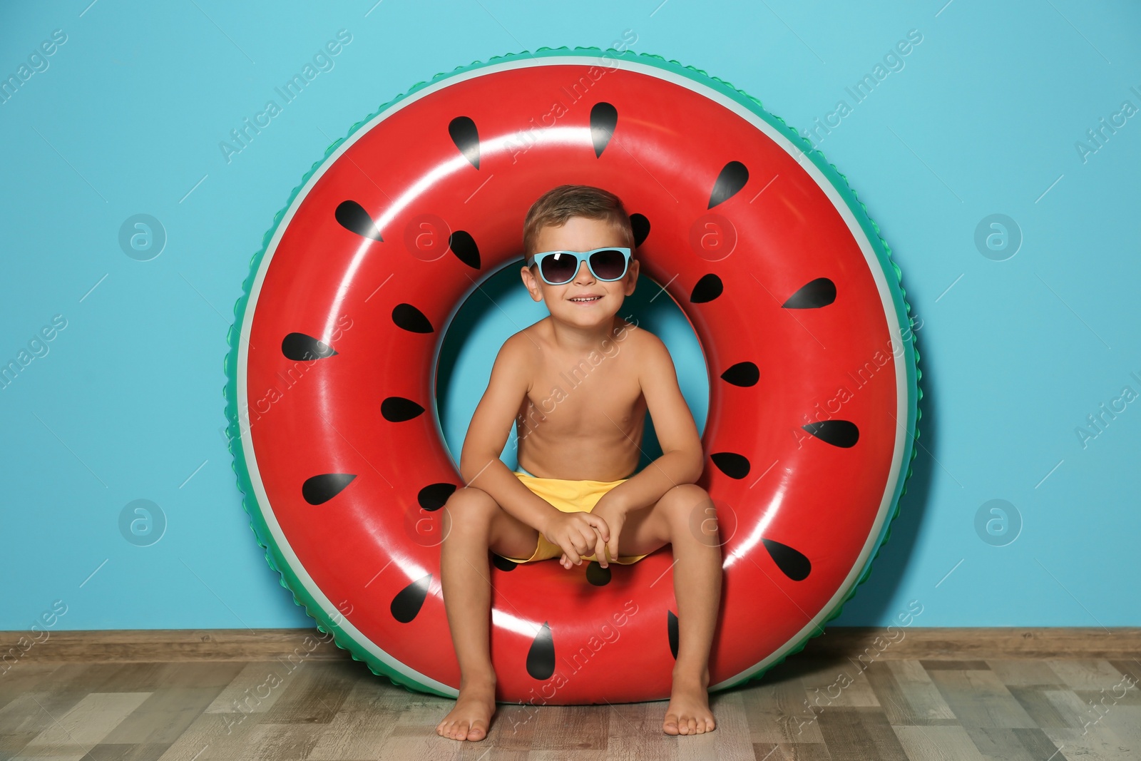 Photo of Cute little boy with inflatable ring near color wall