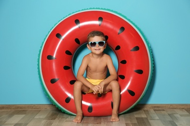 Photo of Cute little boy with inflatable ring near color wall