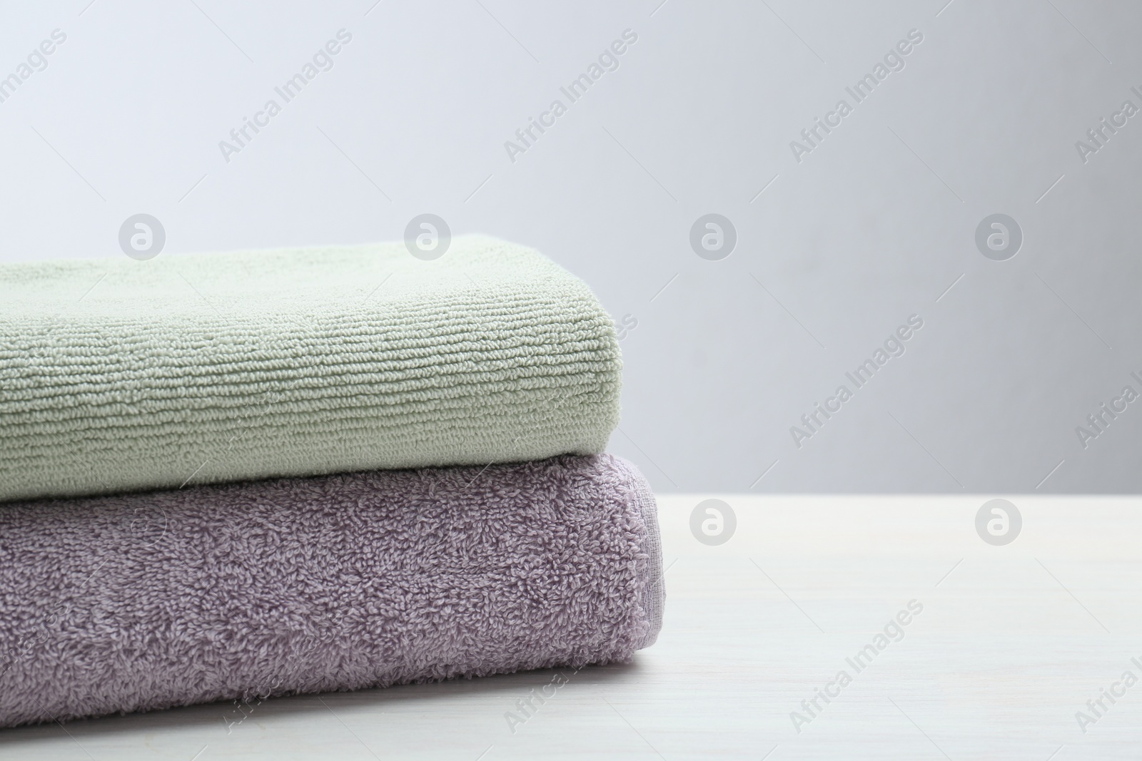 Photo of Different folded towels on white wooden table, closeup. Space for text