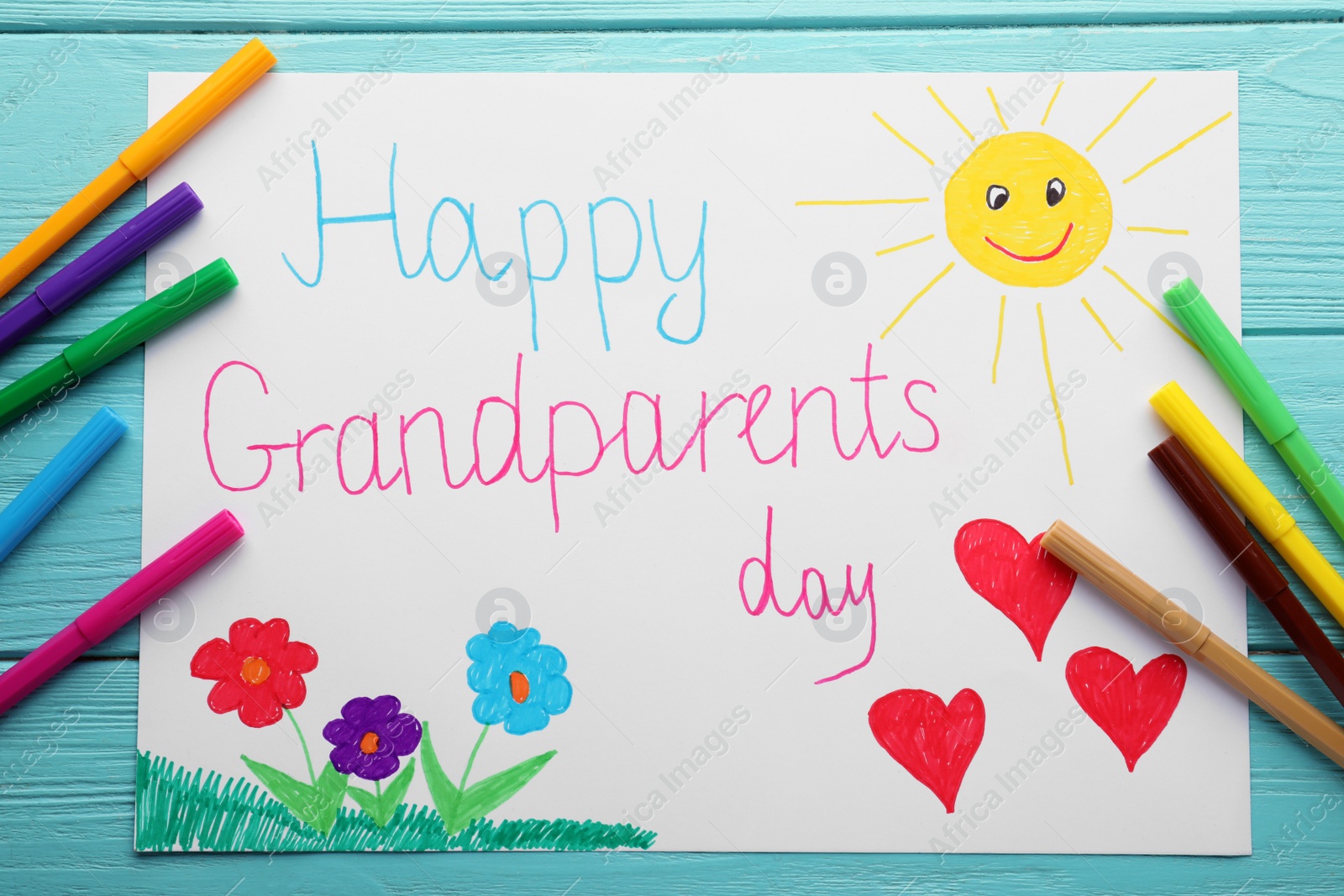 Photo of Beautiful drawing with phrase Happy Grandparents Day on blue wooden table, flat lay