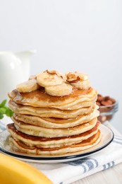 Photo of Tasty pancakes with sliced banana served on white wooden table, closeup. Space for text