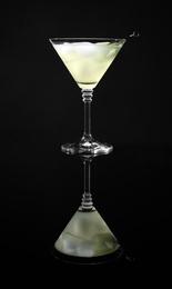 Glass of delicious cucumber martini with ice on dark background