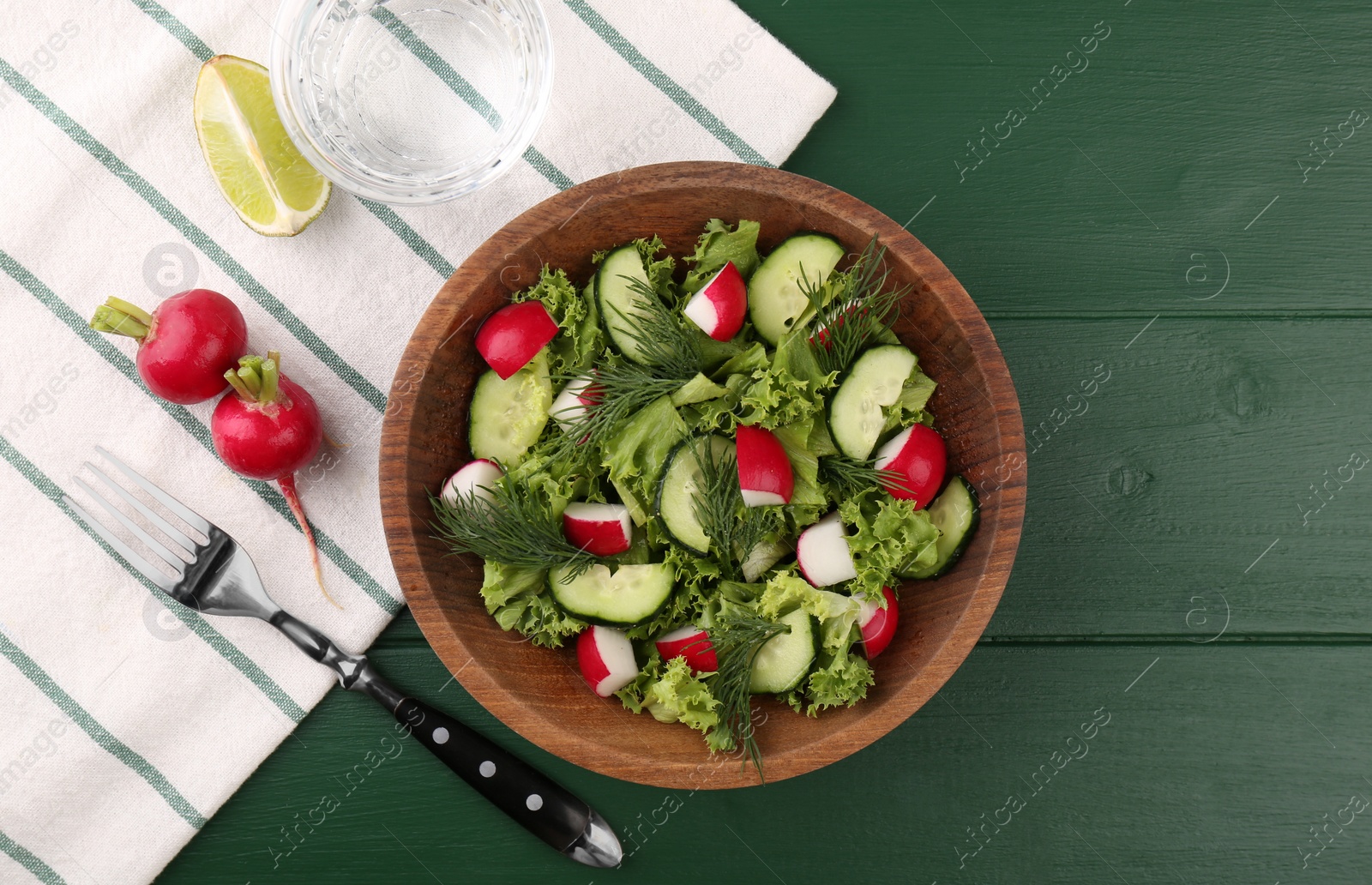 Photo of Delicious salad with radish, lettuce, dill and cucumber served on green wooden table, flat lay