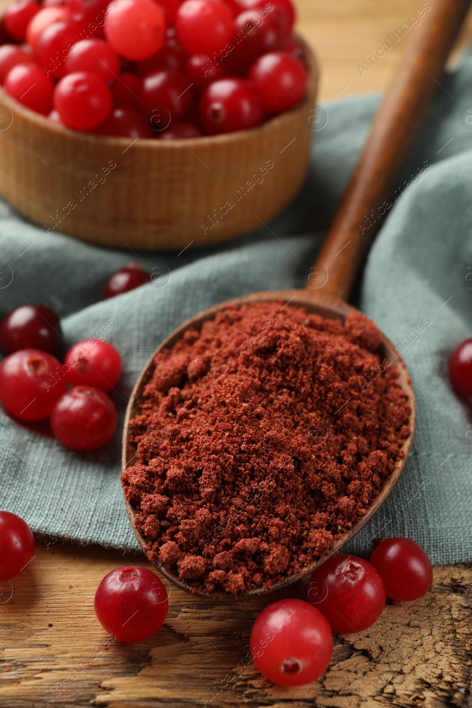 Photo of Spoon with cranberry powder and fresh berries on wooden table, closeup