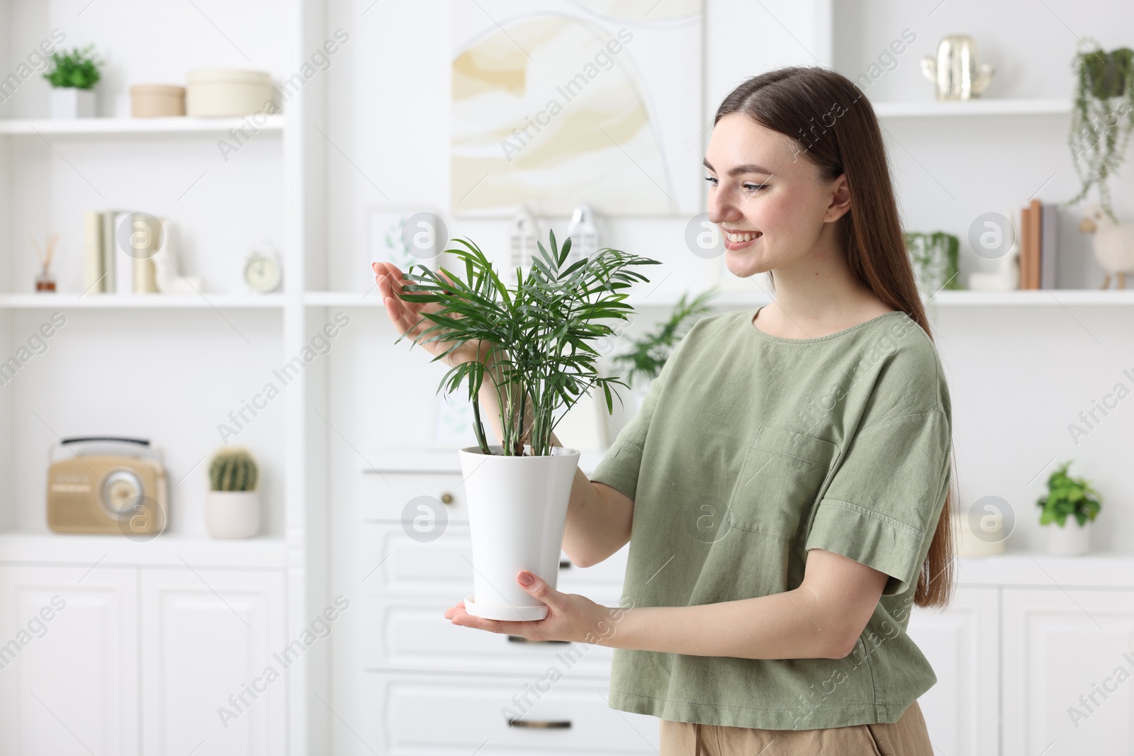 Photo of Beautiful young woman with green houseplant at home, space for text