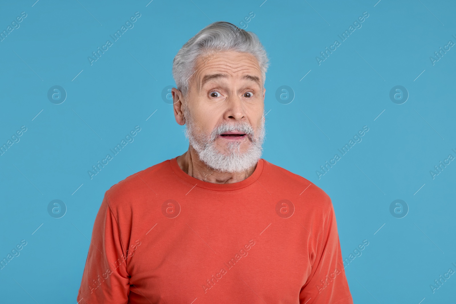 Photo of Portrait of surprised senior man on light blue background