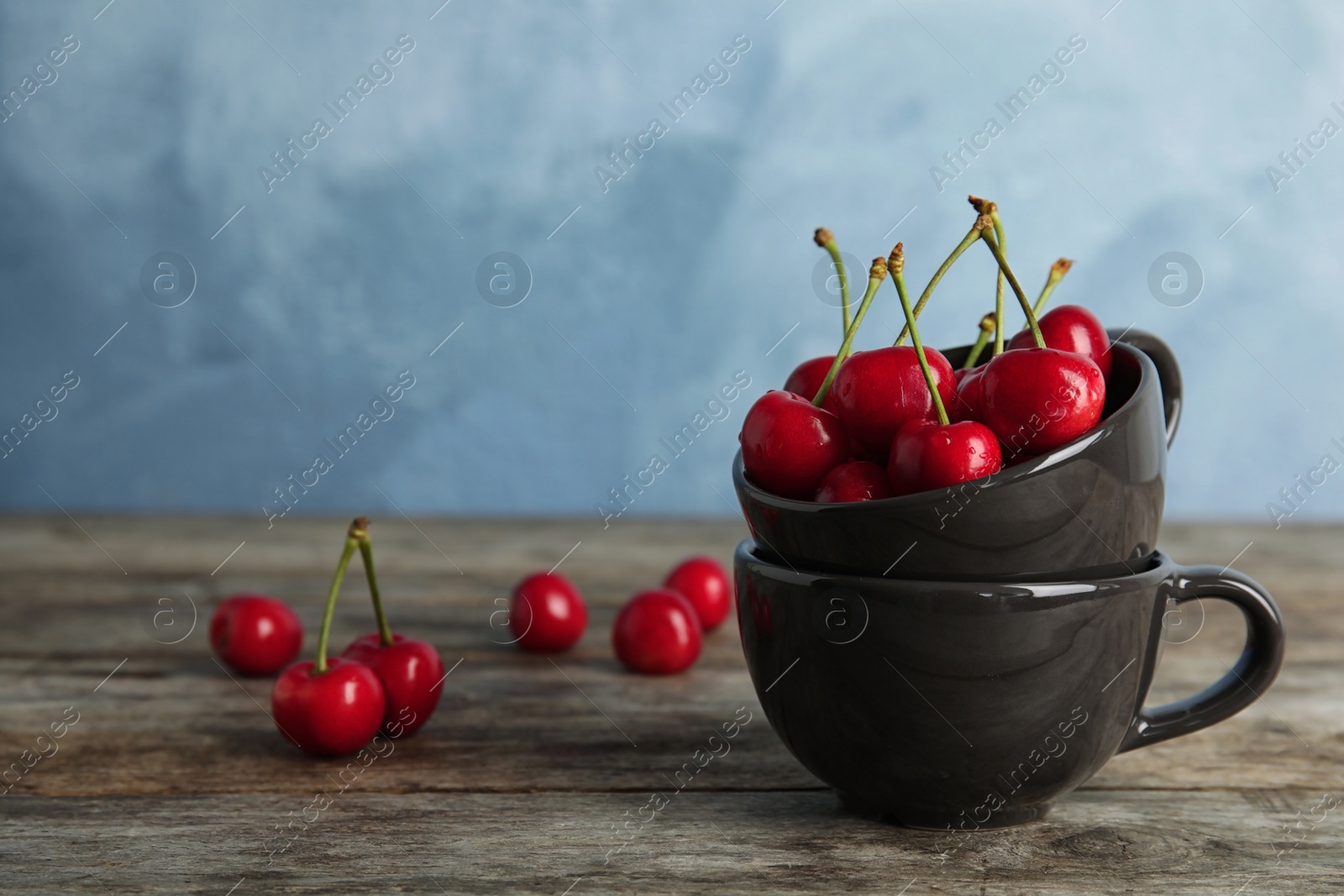 Photo of Cups with sweet red cherries on wooden table