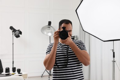 Photo of Professional photographer taking picture in modern photo studio, space for text