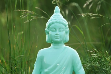 Decorative Buddha statue in green grass outdoors, closeup