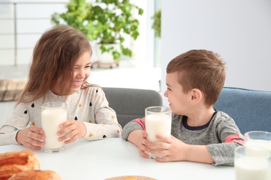 Photo of Cute little kids having breakfast with milk at table