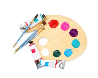 Photo of Wooden artist's palette with brushes and paints on white background, top view