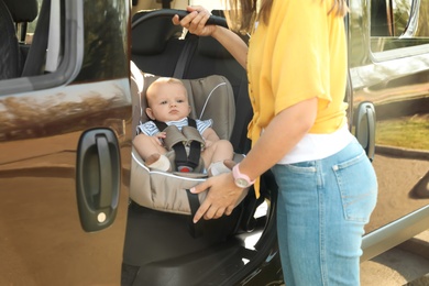 Mother taking child safety seat with baby out of car