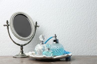 Photo of Plate with perfume bottles and jewellery near mirror on dressing table. Space for text