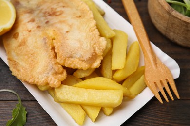 Photo of Delicious fish and chips served on wooden table, closeup