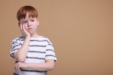 Photo of Portrait of sad little boy on beige background, space for text