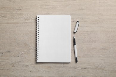 Photo of Empty notebook and pen on wooden table, flat lay