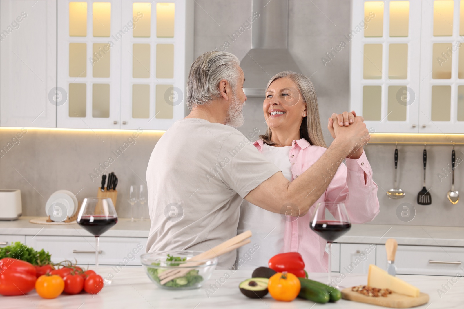 Photo of Happy affectionate senior couple dancing in kitchen