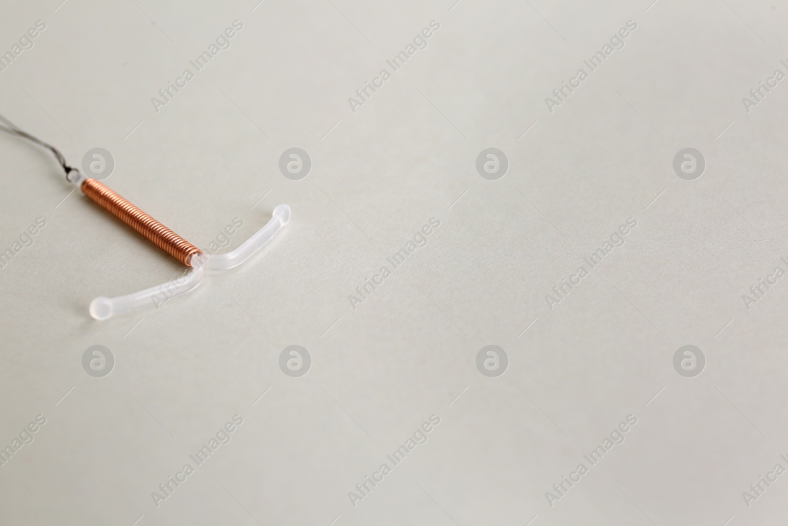 Photo of Copper intrauterine contraceptive device on light background. Space for text