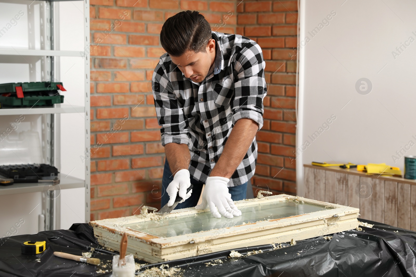 Photo of Man repairing old damaged window at table indoors