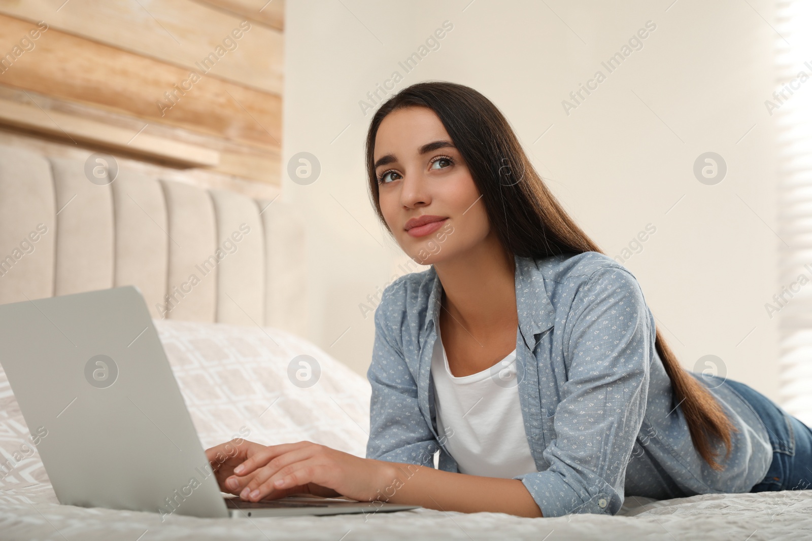 Photo of Woman using laptop for search on bed at home