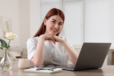 Photo of Beautiful woman with laptop at wooden table in room