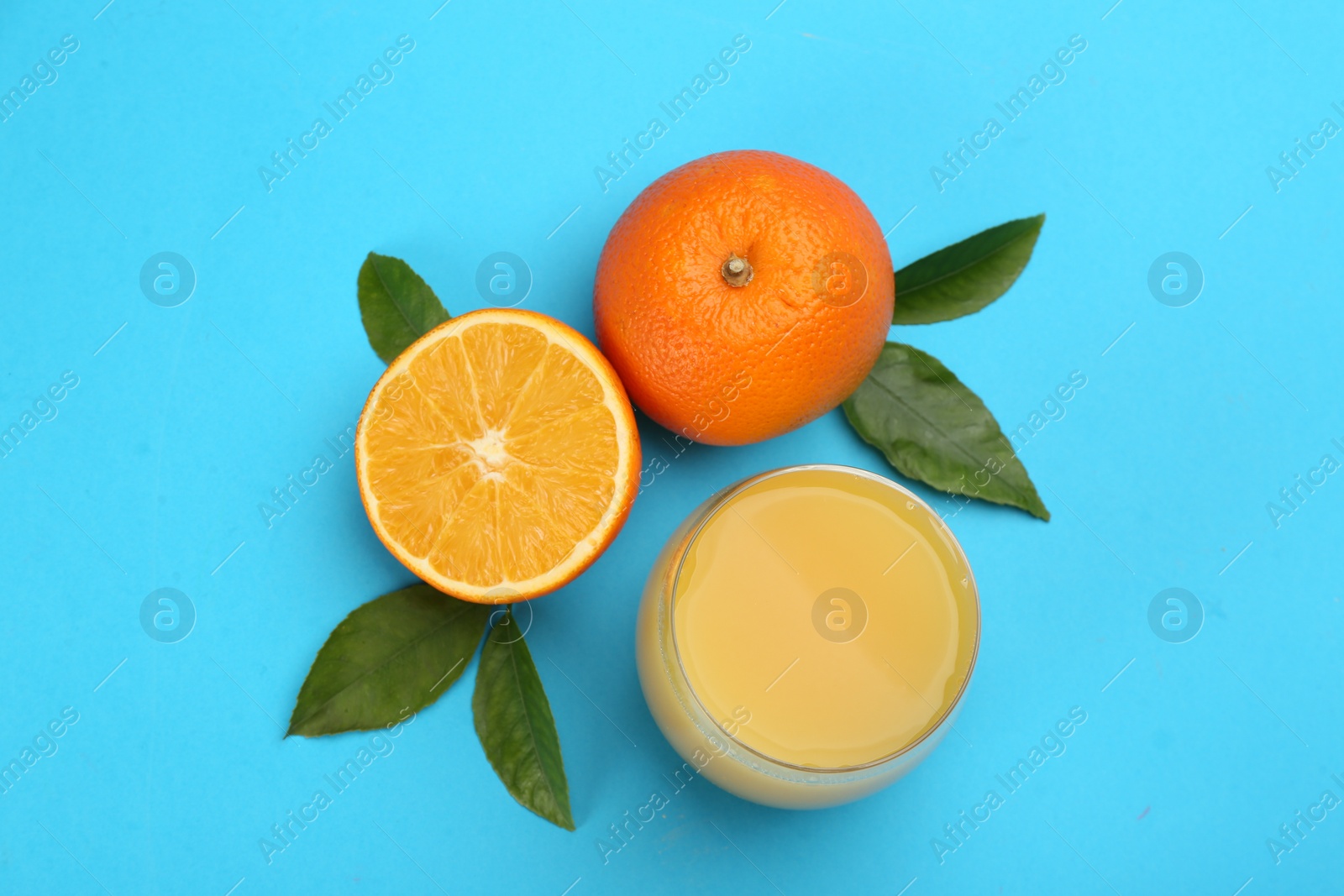 Photo of Delicious orange juice and fresh fruits on light blue background, flat lay