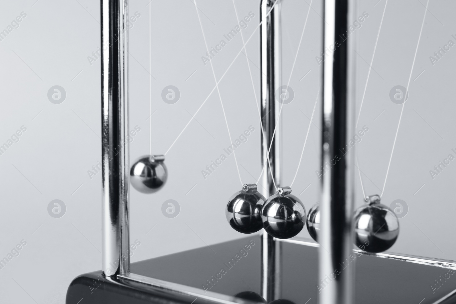 Photo of Newton's cradle on light background, closeup. Physics law of energy conservation