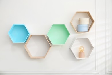 Photo of Honeycomb shaped shelves with decorative elements on white wall