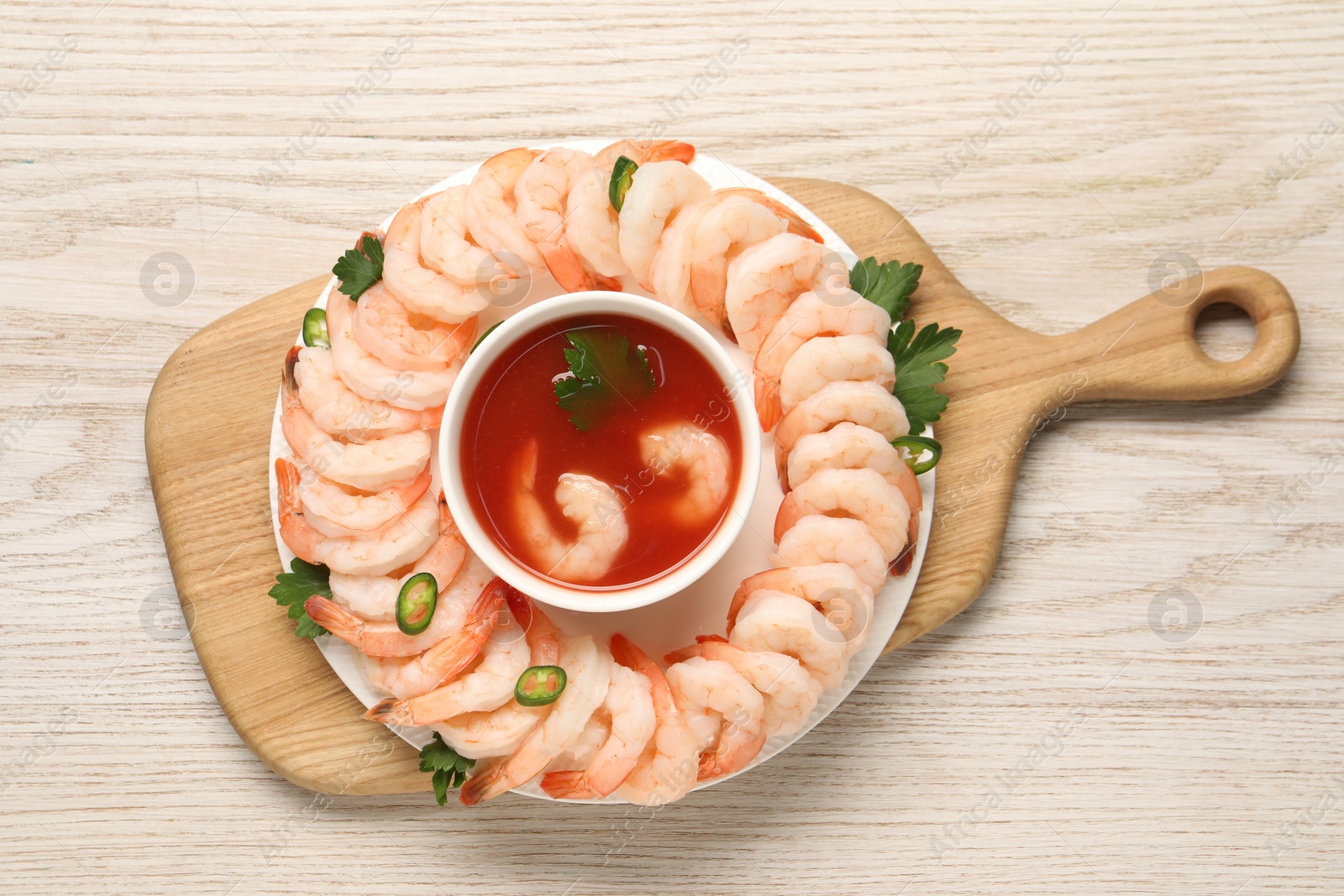 Photo of Tasty boiled shrimps with cocktail sauce, chili and parsley on light wooden table, top view